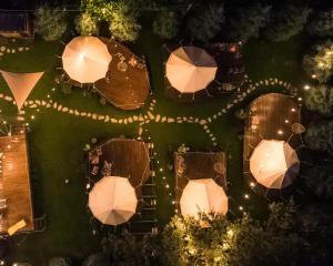 - une vue sur le jardin de nuit avec des parasols dans l'établissement Valea Doftanei Glamping, à Teşila