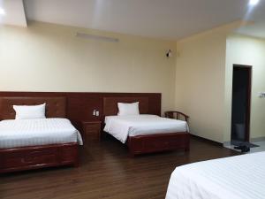 1 dormitorio con 2 camas, sábanas blancas y suelo de madera. en THANH XUÂN HOTEL, en Cao Bằng