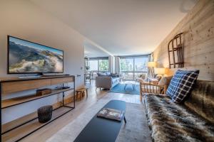 uma sala de estar com um sofá e uma televisão na parede em Apartment Cortirion Megeve - by EMERALD STAY em Megève