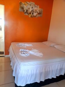 a bed in a room with an orange wall at Hotel 3 irmaos in Três Marias