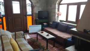 a living room with a couch and a tv at Arachova Houses-Ευήλιον ΛΙΒΑΔΙ in Arachova