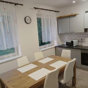 cocina con mesa de madera y sillas blancas en Fakapu Vendégház, en Sárospatak