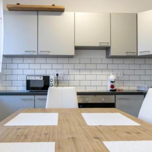 a kitchen with a wooden table and white cabinets at Fakapu Vendégház in Sárospatak