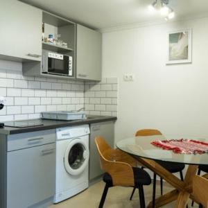 uma cozinha com uma máquina de lavar roupa e uma mesa com cadeiras em Fakapu Vendégház em Sárospatak