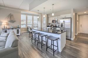 a kitchen and living room with a large island with bar stools at Luxe Manistee Condo with Balcony and River Views! in Manistee