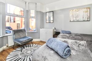 a bedroom with two beds and a chair and windows at City Centre 3 Bed House for Large Groups and Contractors by Amazing Spaces Relocations Ltd in Liverpool