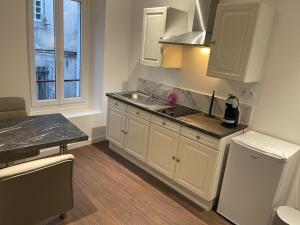 een keuken met witte kasten, een wastafel en een raam bij Les Appartements du Cep’t in Mazamet