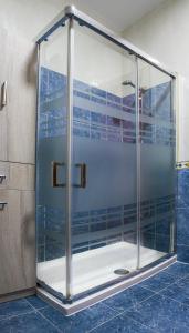 a glass shower in a bathroom with blue tiles at Cerca del puerto deportivo y de la playa in Cangas de Morrazo