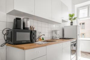 eine weiße Küche mit einer Mikrowelle und einem Kühlschrank in der Unterkunft Spacious 2BR Apt. Rennweg - Perfect for Longstays. in Wien