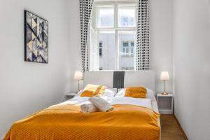 ein Schlafzimmer mit einem Bett mit orangefarbener Bettwäsche und einem Fenster in der Unterkunft Spacious 2BR Apt. Rennweg - Perfect for Longstays. in Wien