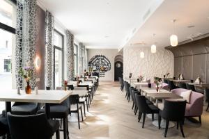 une rangée de tables et de chaises dans un restaurant dans l'établissement elaya hotel regensburg city center, à Ratisbonne