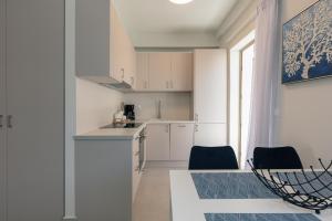 een keuken met witte kasten en een tafel en stoelen bij Harbour Hill Suites in Rethimnon