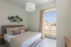 een slaapkamer met een bed en een groot raam bij Harbour Hill Suites in Rethimnon