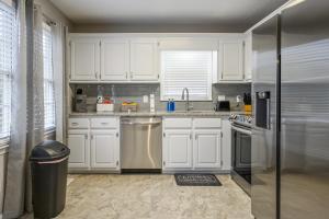 a kitchen with white cabinets and a stainless steel refrigerator at Embrace The Outdoors In This Modern Rydal Setting in White