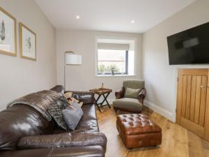 uma sala de estar com um sofá de couro e uma cadeira em Fox's Den em Hull