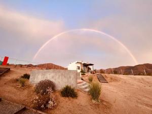 un arco iris en el cielo sobre una casa en el desierto en Huella B, en Guadalupe