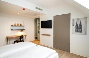a hotel room with two beds and a desk at elaya hotel regensburg city center in Regensburg