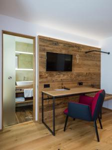 Zimmer mit einem Schreibtisch und einem TV an der Wand in der Unterkunft Landgasthof Lusenblick in Grafenau