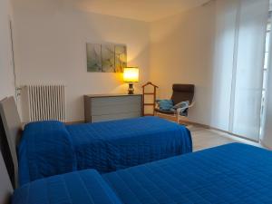 una camera con due letti blu e una sedia di Chez George a Levico Terme