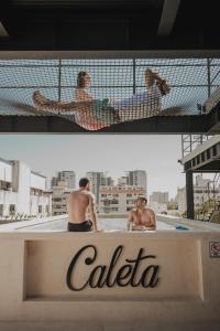 two men are laying in a swimming pool at Caleta Hostel Rooftop & Pool in Cancún