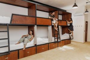 un groupe de personnes assises sur des lits superposés dans l'établissement Caleta Hostel Rooftop & Pool, à Cancún