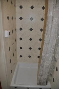 a bathroom with a white tub and a black and white tiles at Hostel Engelberg in Engelberg