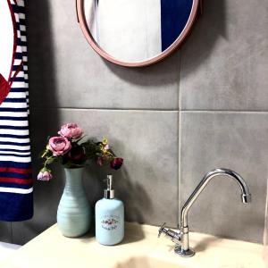 a bathroom sink with a vase of flowers and a mirror at Chalé Recanto dos Anjos Arraial do Cabo in Arraial do Cabo