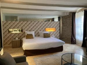 - une chambre avec un grand lit et une grande tête de lit dans l'établissement Art'Hotel & SPA Le Potin Gourmand, à Cluny