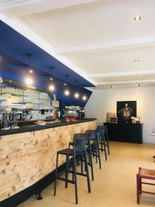 a bar with black stools at a bar with a counter at Hôtel Clair de Lune in Mauguio