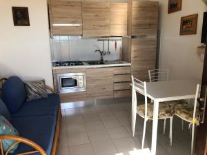 una piccola cucina con tavolo e forno a microonde di Appartamento Iris 300 mt spiaggia a San Teodoro