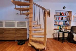 a wooden spiral staircase in a living room with a book shelf at Wohnung mit Garten, Sauna und Infrarotkabine 
