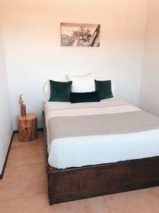 1 dormitorio con 1 cama con sábanas blancas y almohadas verdes en Huella B, en Guadalupe