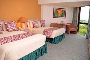 a hotel room with two beds and a table at Tibisay Hotel Maturin in Maturín