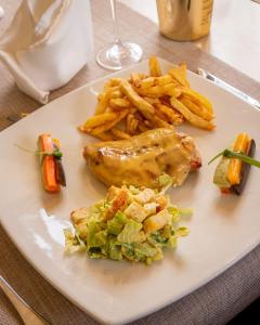 a white plate with food and french fries on a table at Tibisay Hotel Maturin in Maturín