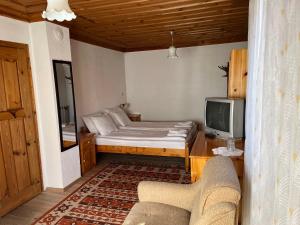 um pequeno quarto com uma cama e uma televisão em Guest House Lina em Koprivshtitsa
