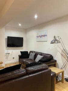 a living room with a leather couch and a flat screen tv at City Center House, Cardiff, parking permit and garden in Cardiff