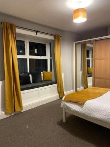 a bedroom with a bed and a window with yellow curtains at City Center House, Cardiff, parking permit and garden in Cardiff