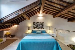 Un dormitorio con una cama con sábanas azules y techos de madera. en La Colombaia Nel Castello, en Bracciano