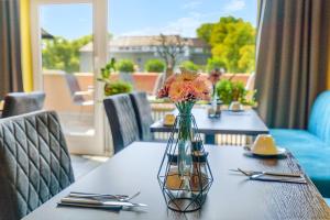 uma mesa com um vaso de flores em cima em Hotel garni Marktterrassen em Hennef