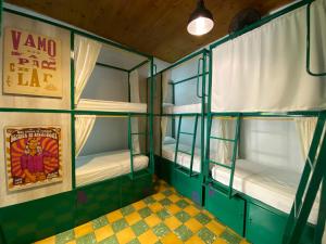 een kamer met groene stapelbedden en een bord waarop staat vmo rate la bij Viajero Hostel Cali & Salsa School in Cali