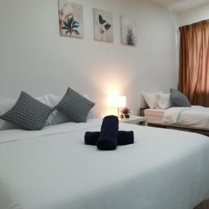 uma cama branca com um bicho de peluche sentado nela em NH Homestay Trefoil em Kuala Selangor