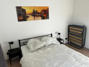 Un dormitorio con una cama blanca con una foto en la pared en Villa Model, en Buonabitacolo