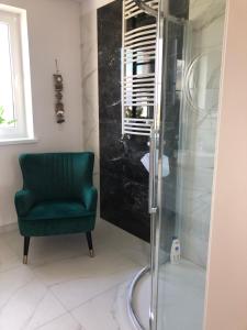 a bathroom with a shower and a green chair at Apartament Kendal in Dźwirzyno