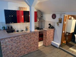 a kitchen with red cabinets and a brick wall at Apartament in regim hotelier in Timişoara