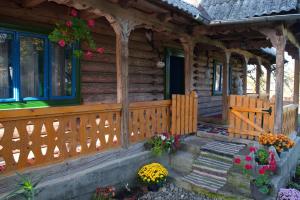 a wooden cabin with a porch and flowers on the porch at La Rodica in Vale in Ocna Şugatag