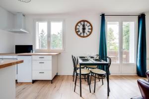 una cocina con mesa y sillas y un reloj en la pared en Le Petit Calypso, en Nancy