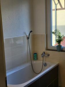 Das Bad ist mit einer Badewanne mit einer Dusche ausgestattet. in der Unterkunft Modernes behagliches Haus mit Kamin, Terrasse und Garten in Magdeburg
