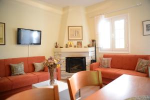 a living room with orange couches and a fireplace at ZeusPlace Valentina's house Elatochori in Elatochori