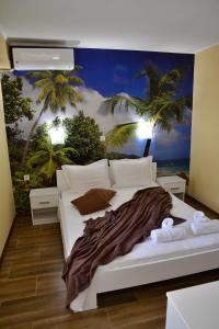 a bedroom with a white bed with a palm tree mural at VILLA IBIS THASSOS in Chrysi Ammoudia