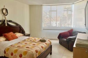 um quarto com uma cama, uma cadeira e uma janela em Lindo y Céntrico MiniDepartamento I em Trujillo